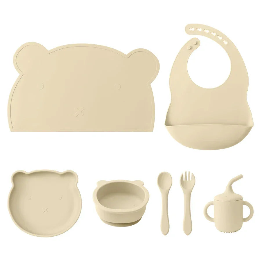 set pappa silicone neonati 7 pezzi beige bavaglino piatto ciotola tazza posate sfondo bianco