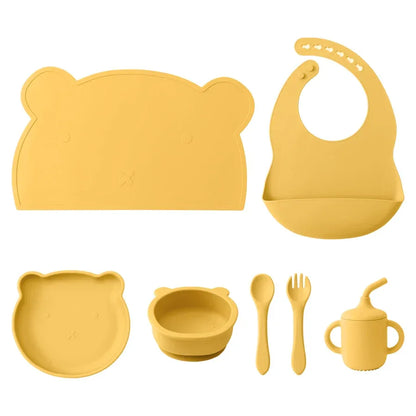 set pappa silicone neonati 7 pezzi giallo bavaglino piatto ciotola tazza posate sfondo bianco
